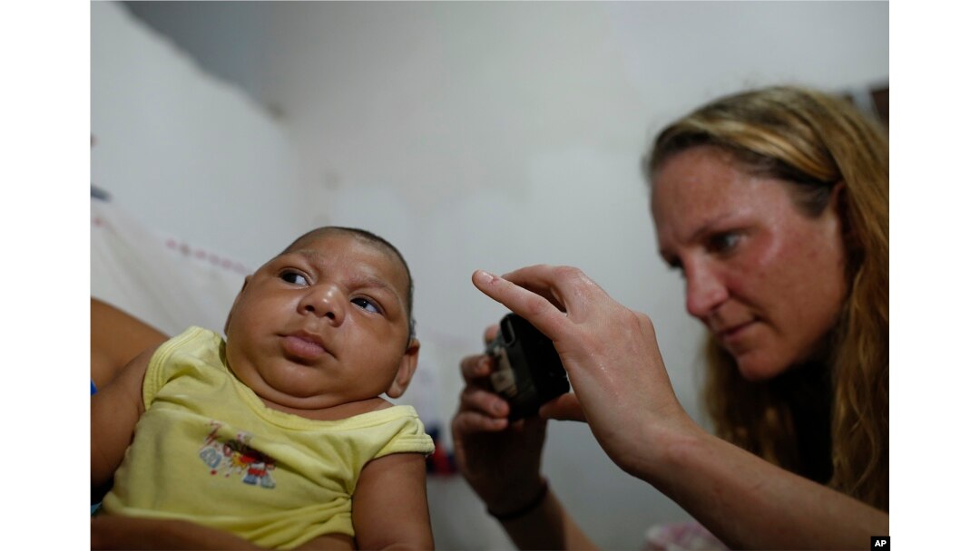 Pediatrician Alexia Harrist from the United States' Centers for Disease Control and Prevention (CDC) takes a picture of 3-month-old Shayde Henrique who was born with microcephaly, after examining him in Joao Pessoa, Brazil, Feb. 23, 2016.