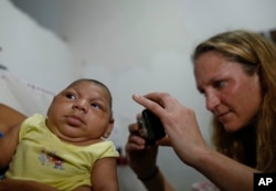 Pediatrician Alexia Harrist from the United States' Centers for Disease Control and Prevention (CDC) takes a picture of 3-month-old Shayde Henrique who was born with microcephaly, after examining him in Joao Pessoa, Brazil, Tuesday, Feb. 23, 2016.