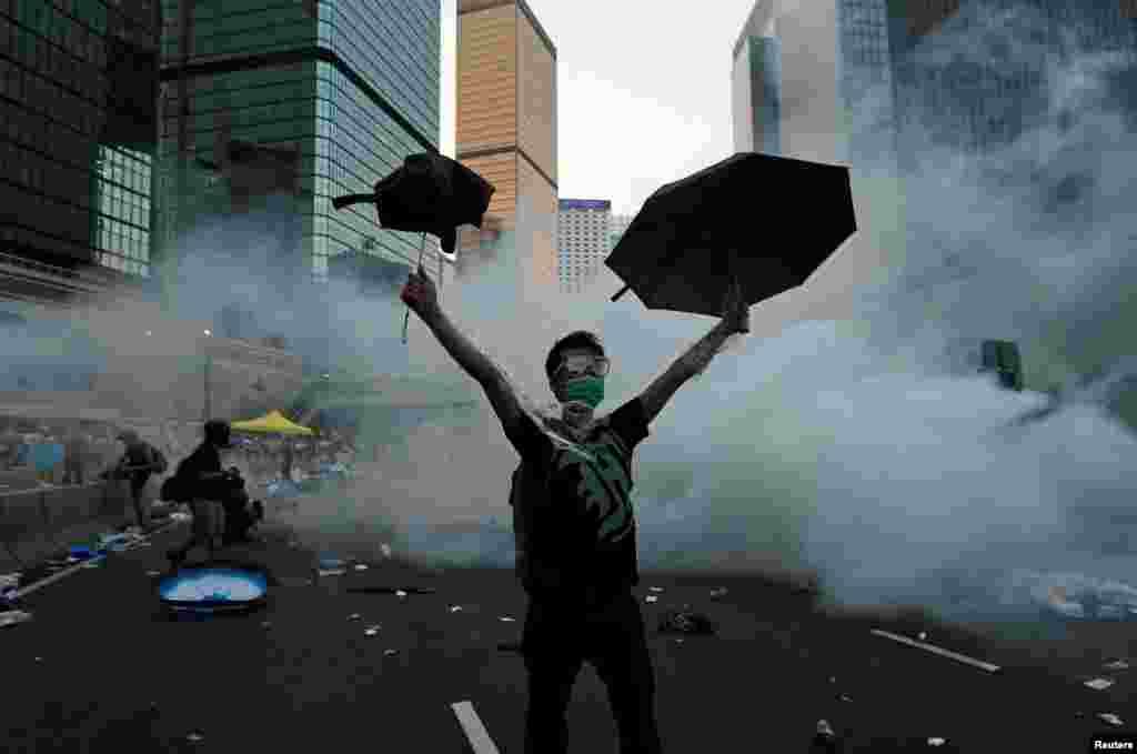 A protester raises his umbrellas after riot police fire tear gas to disperse protesters in Hong Kong, Sept. 28, 2014. Large-scale protests calling for a fully democratic vote to choose Hong Kong's next leader. Umbrellas became the symbol of the campaign.
