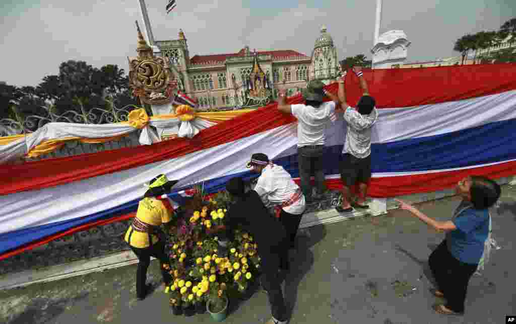 Anti-government protesters hold a long Thai national flag on the gate and fence around the prime minister's office, known as Government House, in Bangkok, Dec. 13, 2013. 