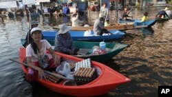 ແມ່ຄ້າພໍ່ຄ້າໄທພາກັນຂາຍເຄື່ອງຢູ່ໃນເຮືອ ຢູ່ຕະຫລາດແຫ່ງນຶ່ງທີ່ຖືກ ນໍ້າຖ້ວມ ທີ່ຈັງຫວັດນົນທະບູຣີ ນອກນະຄອນຫລວງບາງກອກ, ວັນທີ 17 ພະຈິກ 2011.