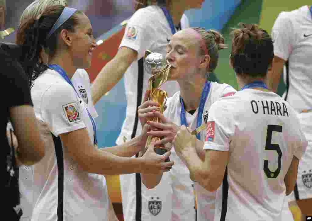 Jogadora americana Becky Sauerbrunn beija o troféu enquanto as jogadoras Kelley O'Hara e Lauren Holiday esperam a sua vez, depois da vitória por 5-2 dos EUA contra o Japão no Mundial Feminino da FIFA em Vancouver, Canadá, no Domingo, 5 de Julho, 2015.