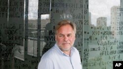 FILE - Eugene Kaspersky, Russian antivirus programs developer and chief executive of Russia's Kaspersky Lab, stands in front of a window decorated with programming code's symbols at his company's headquarters in Moscow, July 1, 2017. 