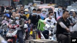 在这张日期为 2021 年 7 月 2 日星期五的文件照片中，北京高峰时段骑自行车和踏板车的人们等待穿过十字路口。联合国气候变化官员于 2021 年 7 月 31 日星期六表示，中国未能提交减少温室气体排放的新目标，其中数十个未能在 7 月 31 日截止日期前提供其计划的最新信息。 （美联社照片）