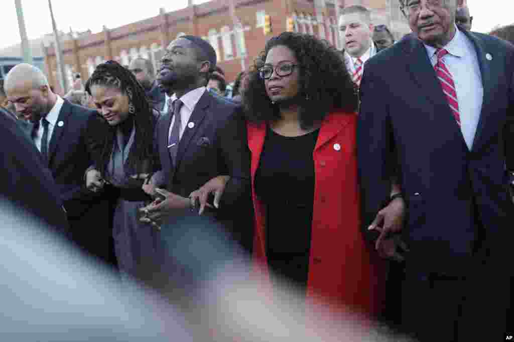 Oprah Winfrey locks arms with David Oyelowo (left) who portrays Martin Luther King, Jr. in the movie "Selma," Ava DuVernay, the director of "Selma" and rapper Common (far left) as they march to the Edmund Pettus Bridge in honor of Martin Luther King Jr., Selma, Alabama, Jan. 19, 2015.