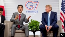 Japanese Prime Minister Shinzo Abe, left, accompanied by U.S President Donald Trump, speaks at a news conference at the G-7 summit in Biarritz, France, Sunday, Aug. 25, 2019, where they announced that the U.S. and Japan have agreed in principle on a new t