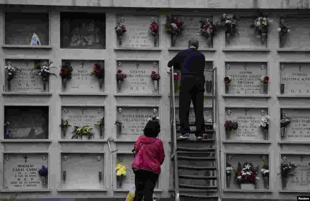 People place flowers on tombs at the municipal cemetery of San Salvador in Oviedo, Spain, Oct. 30, 2017.