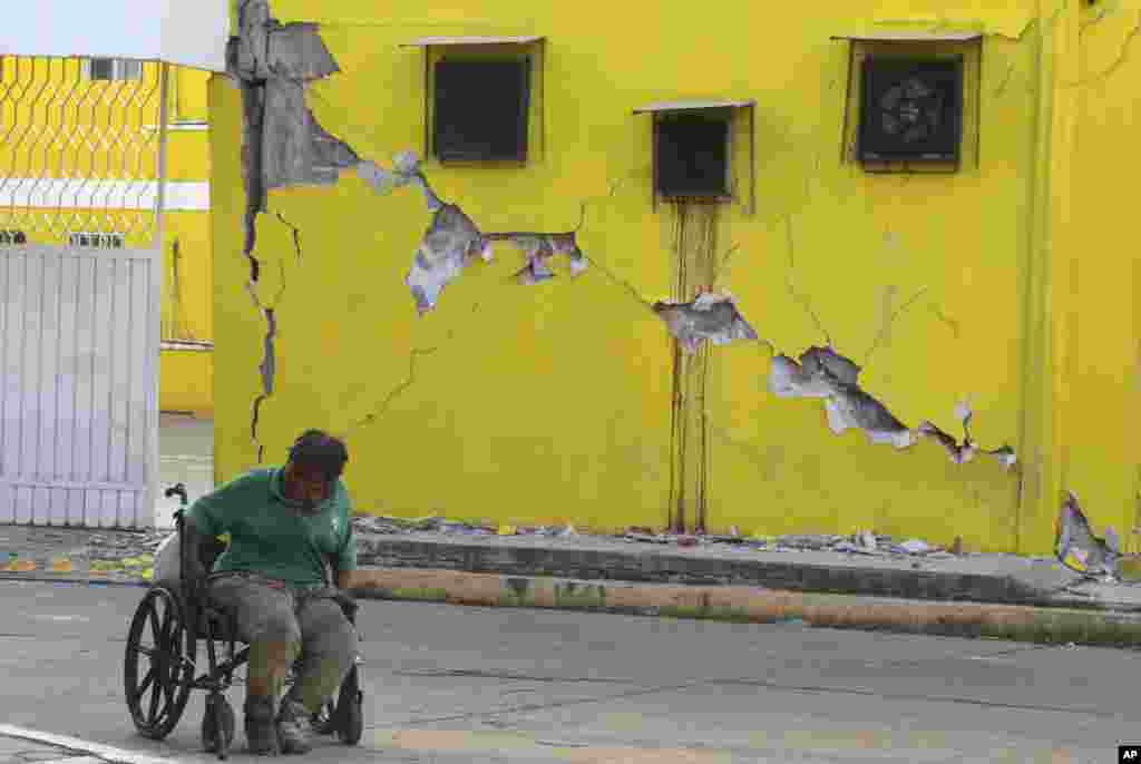 A man sits in his wheelchair in front of a building damaged in a massive earthquake, in Juchitan, Oaxaca state, Mexico. One of the most powerful earthquakes ever to strike Mexico hit off its southern Pacific coast late Thursday, killing at least 32 people.