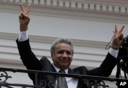 FILE - Ecuador's President Lenin Moreno flashes victory hands as he greets supporters from the Government Palace's balcony during the weekly Changing of the Guard, in Quito, Ecuador, Feb. 5, 2018.