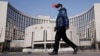 一名戴着口罩的男子走过北京的中国人民银行总部。（2020年2月3日）