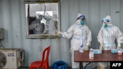 ရန်ကုန်မြို့ Quarantine Center တခုမှာ COVID ရောဂါရှိ၊ မရှိ Swab နမူနာယူ စစ်ဆေးပေးဖို့ ပြင်ဆင်နေကြတဲ့ PPE ဝတ်စုံဝတ်ဆင်နေကြသည့် ကျန်းမာရေးဝန်ထမ်းများ။ (အောက်တိုဘာ ၁၃၊ ၂၀၂၀)