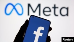A smartphone with Facebook's logo is seen in front of displayed Facebook's new rebrand logo Meta in this illustration taken Oct. 28, 2021. 
