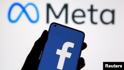 A smartphone with Facebook's logo is seen in front of displayed Facebook's new rebrand logo Meta in this illustration taken Oct. 28, 2021. 