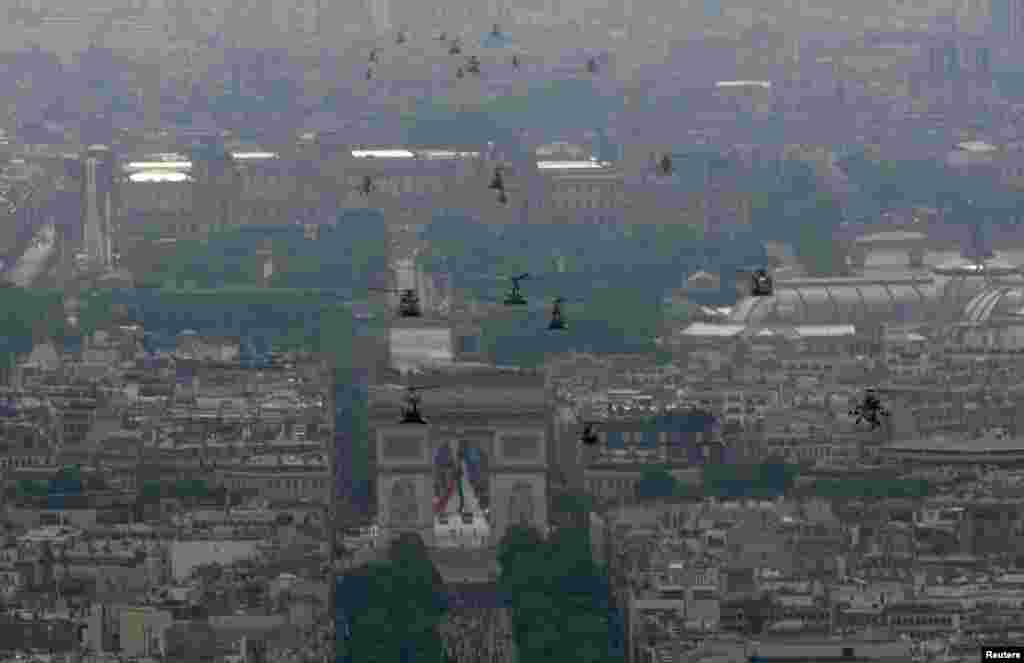 French army helicopters approach the Arc de Triomphe during the Bastille Day parade in Paris, July 14, 2014.