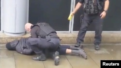 A police officer points a taser while the other holds a man down outside Arndale shopping center, where several people have been stabbed, in Manchester, Britain October 11, 2019 in this still image taken from a social media video. JOHN GREENHALGH via REUT