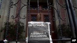 Una copia de la portada del periódico El Periódico de Guatemala, que se lee "Periodistas muertos", cuelga en una puerta principal de la Casa Presidencial durante una protesta exigiendo una investigación por unos comunicadores asesinados.