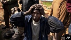 A suspected mercenary from Chad keeps his hands on his head after being detained by Libyan militia member from the forces against Libyan leader Moammar Gadhafi at a roadblock near Marj in eastern Libya, February 27, 2011