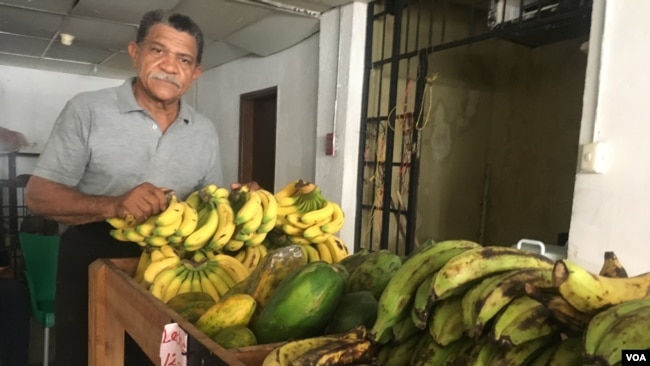 José Pulgar, ayuda a vender productos, frutas y verduras en un mercado de Maracaibo, donde los clientes generalmente pagan en dólares.