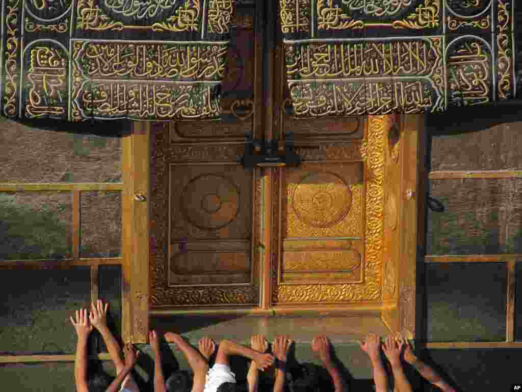 Des pèlerins musulmans prient devant la porte de la Kabaa, la structure en forme de cube qui se trouve dans la Grande Mosquée de La Mecque en Arabie Saoudite, vers laquelle se tournent les musulmans du monde entier en prière cinq fois le jour (photo du 13 octobre 2013)