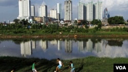 Anak-anak Indonesia bermain bola di pinggir sebuah sungai di Jakarta. Pemerintah Indonesia diharapkan bisa mewujudkan pertumbuhan ekonomi untuk menciptakan kesejahteraan.