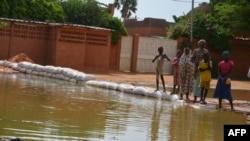 Quelques personnes dans une rue inondée par le fleuve Niger dans le quartier Saga de Niamey le 11 septembre 2017.