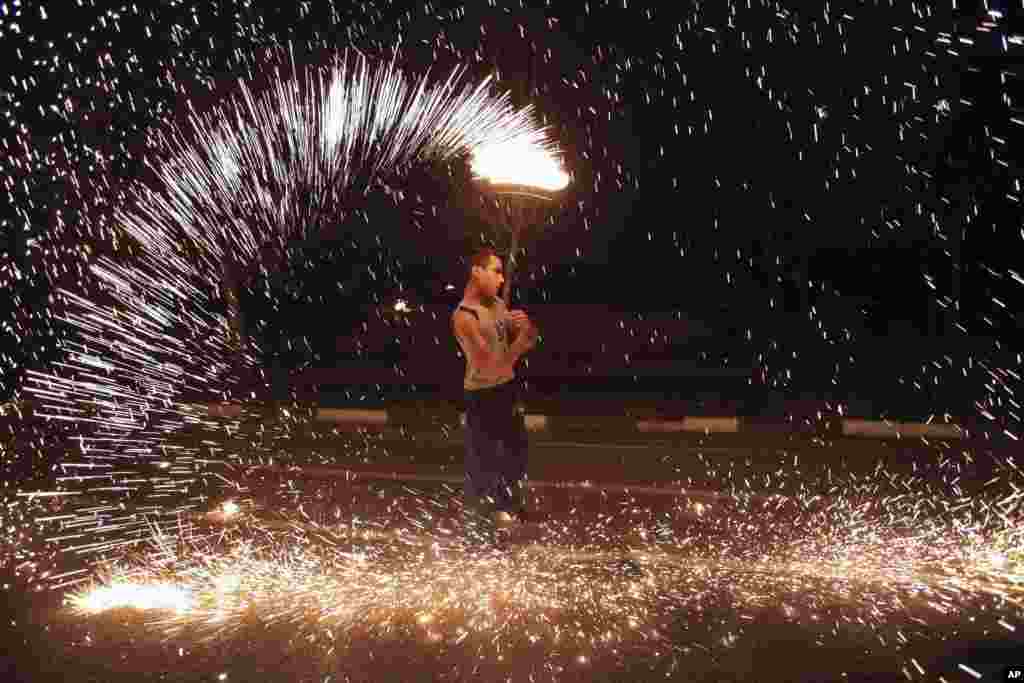 Một người đàn ông Iran chơi với pháo hoa trong công viên Pardisan ở Tehran, ngày 18 tháng 3, 2014, trong lễ hội Chaharshanbe Souri (lễ hội Lửa). Người Iran nhảy qua đống lửa đang bừng cháy và ném pháo để đón mừng mùa xuân tới, trùng với dịp lễ năm mới truyền thống của họ, được gọi là Nowruz, bắt đầu từ ngày 21 tháng 3.