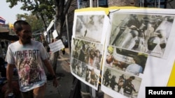 An anti-government protester walks past pictures taken during clashes with riot policemen, during a rally outside the Government House in Bangkok December 29, 2013.
