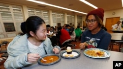 Foreign exchange student Miaofan Chen, left, of Hefei, China, chats with Thandi Glick during a potluck meal for Chinese exchange students and their families at a school in Denver, Jan. 27, 2017.
