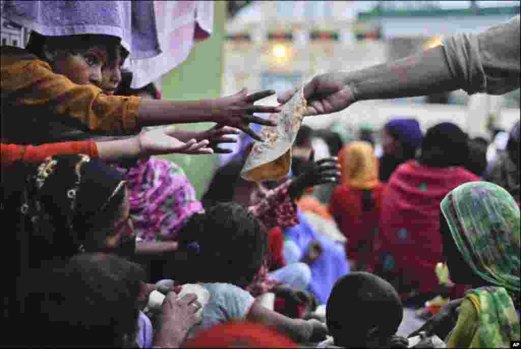 Children reach out to receive bread being donated for iftar at the Bari Imam Sufi shrine in Islamabad