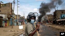 Un policier tient un pistolet lors d'une manifestation dans le bidonville de Kariobangi à Nairobi, au Kenya, le 8 mai 2020. (AP Photo/Brian Inganga)