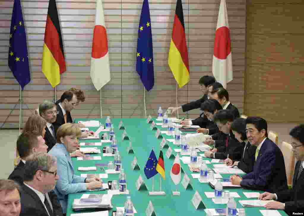 Kanselir Jerman Angela Merkel berbicara dengan Perdana Menteri Shinzo Abe (kedua dari kanan) dalam pertemuan di kediaman Abe di Tokyo (9/3). (Reuters/Kimimasa Mayama)