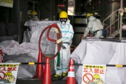 Pekerja mengenakan pakaian hazmat, membawa selang di fasilitas pengolahan air di PLTN Fukushima Dai-ichi di Okuma, Prefektur Fukushima, Jepang, 12 Februari 2020.
