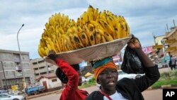 FILE - Women sell bananas on a street in Kampala, Uganda, March 26, 2020. 