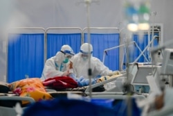 FILE - This photo taken on December 19, 2020 shows healthcare workers wearing personal protective equipment (PPE) as they talk to a patient with the Covid-19 coronavirus at the Ayeyarwady Covid Center at the Thuwana football stadium in Yangon.