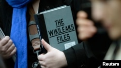 FILE - A supporter of WikiLeaks founder julian Assange holds a copy of The WikiLeaks Files outside the Ecuadorian embassy in central London, Britain Feb. 5, 2016. 