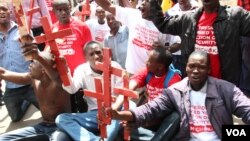 Protesters holding red crosses symbolizing victims of terror attacks are seen gathered outside the President's Office in Nairobi, Kenya, Nov. 25, 2014. (Mohammed Yusuf/VOA)