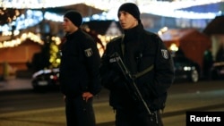 German police officers patrol with machine guns at a Christmas market on Breitscheidplatz square near the fashionable Kurfuerstendamm avenue in the west of Berlin, Germany, Dec. 19, 2016.