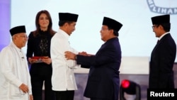 Capres 01 Joko Widodo (kiri) berjabat tangan dengan Capres 02 Prabowo Subianto sementara Cawapres 01 Ma'ruf Amin dan Cawapres 02 Sandiaga Uno menyaksikan usai debat pertama di Jakarta, Kamis malam (17/1).