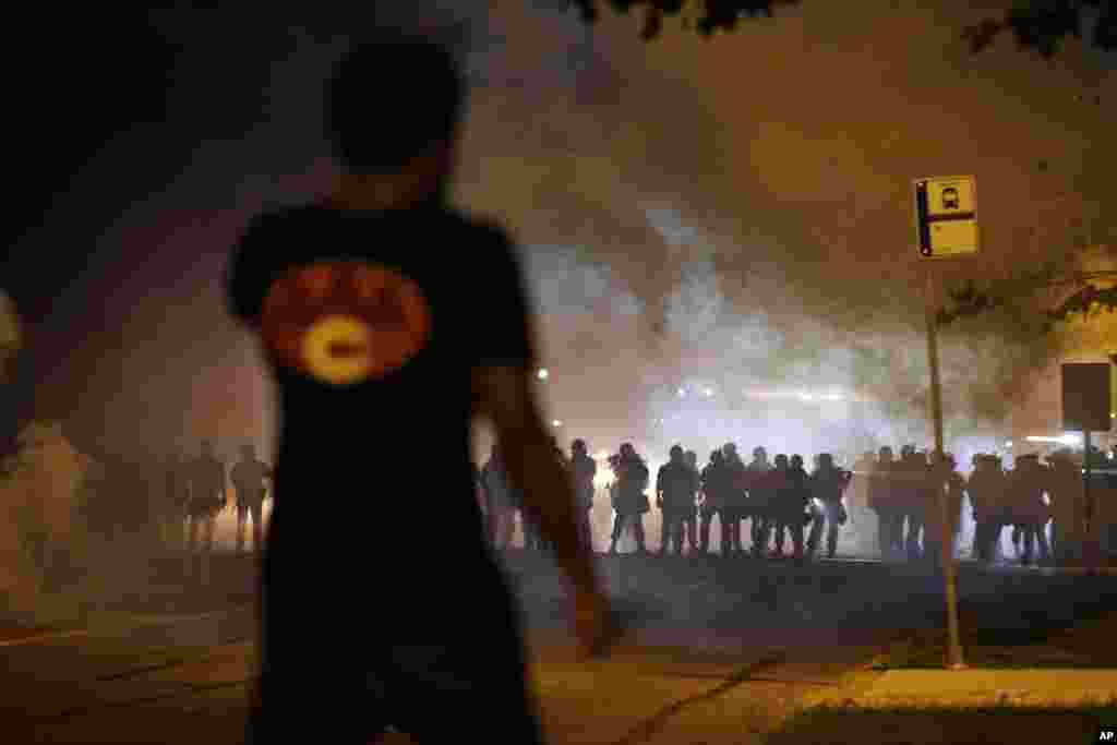 A nuvem de fumo separa um manifestante e a polícia que caminha na sua direcção, durante os confrontos, em Ferguson, Missouri, Ago. 13, 2014.