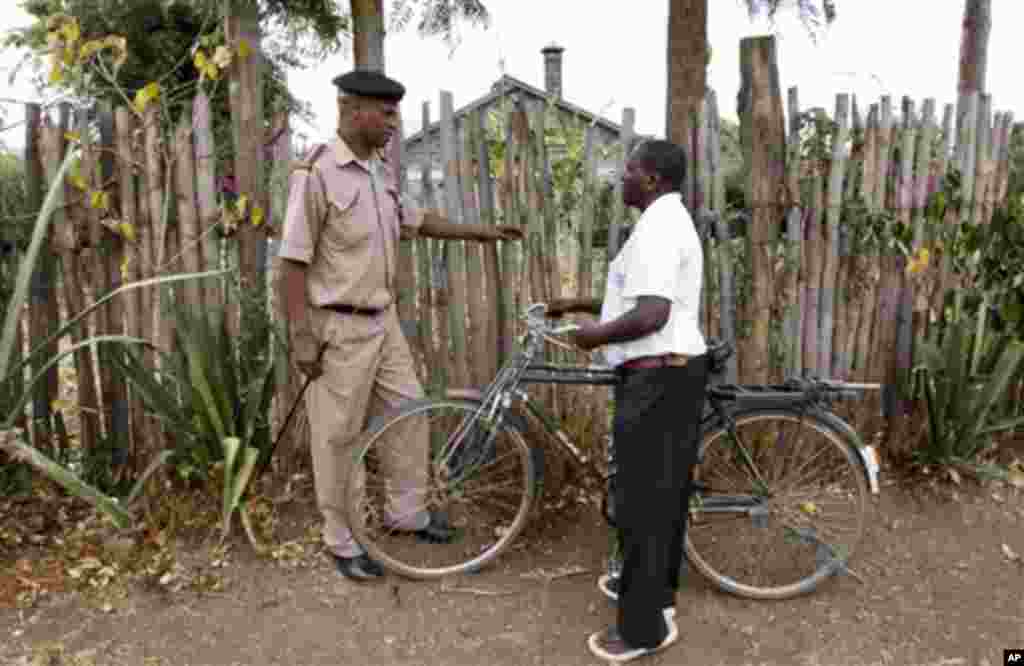 In this photo taken Monday, Feb. 13, 2012, Chief Francis Kariuki, left, is shown a gap in a fence that thieves escaped through, by village elder Peter Ndungu, right, in the village of Lanet Umoja, near Nakuru, in the Rift Valley of Kenya. Kariuki's latest