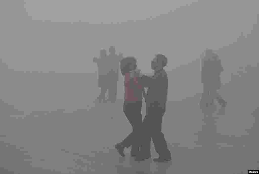 یک زوج با ماسک در هوای آلوده یک شهر صنعتی در چین می رقصند.