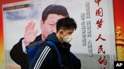 北京街道上,戴口罩的行人走过带有中国领导人习近平像的海报,海报上有标语“中国梦人民的梦”(2017年10月26日)