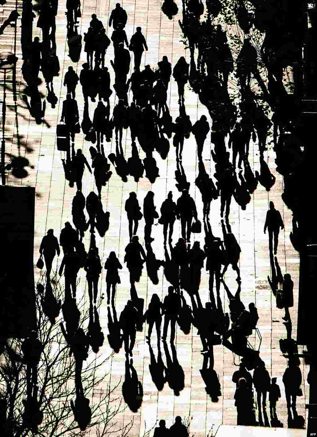 The silhouettes can be seen of the people walking on a street in Stuttgart, Germany.