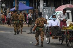 FILE - Soldiers walk along a street as they search for protesters, who took part in a demonstration against the military coup, in downtown Yangon, Myanmar, May 6, 2021.