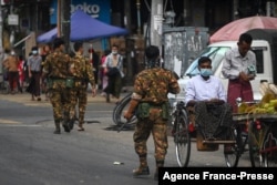 FILE - Soldiers walk along a street as they search for protesters, who took part in a demonstration against the military coup, in downtown Yangon, Myanmar, May 6, 2021.