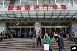 People walk past an entrance to Ruijin Hospital, Oct. 25, 2018, in Shanghai. Doctors at Ruijin have tried to turn the hospital into a center of deep brain stimulation research.