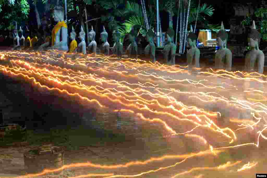 태국 아유타야의 야이차이몽콘 사원에서 진행된 부처님 오신날 기념행사에서 신도들이 촛불을 밝히고 있다. 저속 촬영으로 빛이 이어져보인다.