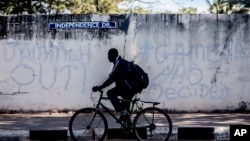 A man rides his bicycle past graffiti on a wall in Banjul, Gambia, Jan. 24, 2017. Journalists have launched a self-regulatory body that they hope will offer legitimacy, and far more freedom, to media emerging from a dictatorship that ruled the country for more than two decades.