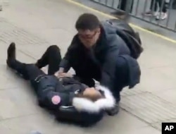 In this image taken from cellphone video provided to the Associated Press, a man tends to an injured person after a minivan carrying gas tanks plowed into pedestrians along a street in Shanghai, Feb. 2, 2018. More than a dozen people were sent to hospitals.