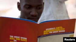 FILE - A man reads a publication by a civil society coalition on human rights and constitutional law in Kampala.